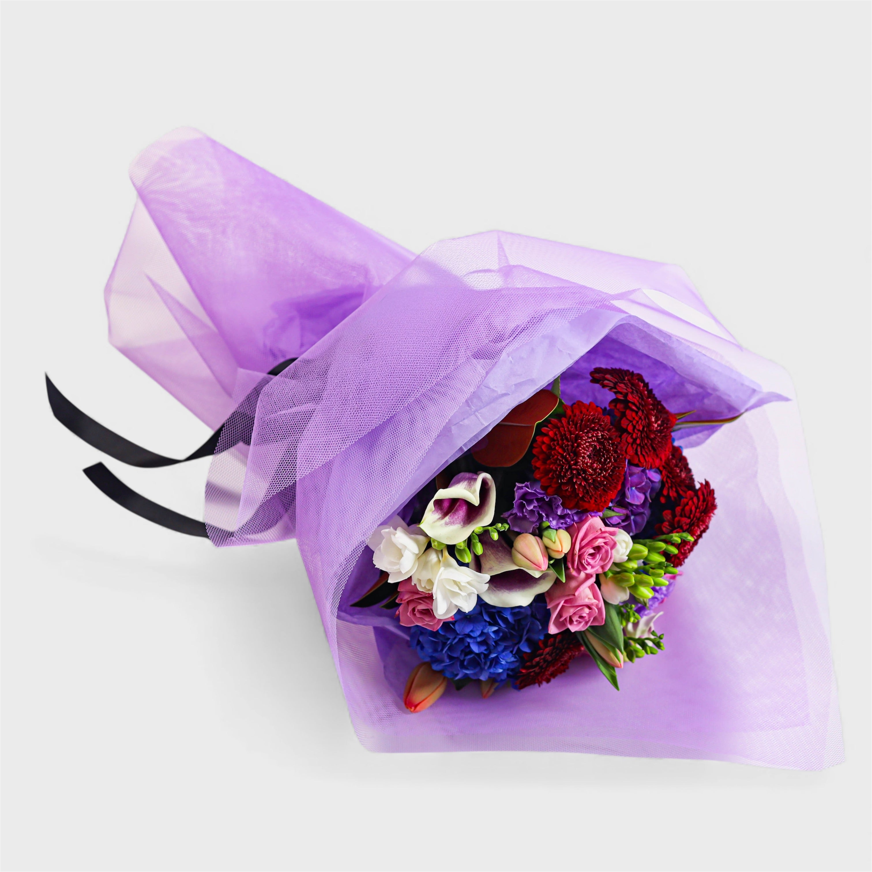 Bouquet of flowers wrapped in purple tissue paper and Tulle